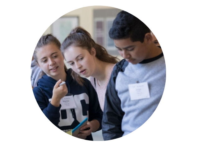 young students stand together looking at something not captured in the photo